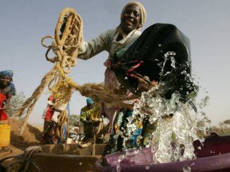Keita, Niger: une agricultrice transvase de l’eau d’un puits à un seau pour arroser ses cultures.