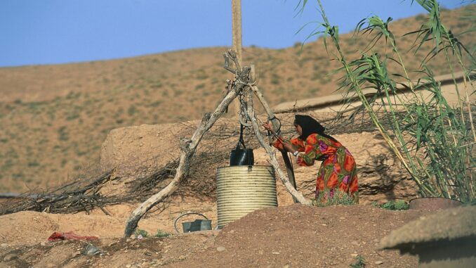 Berber woman drawing water from well, Dades valley
